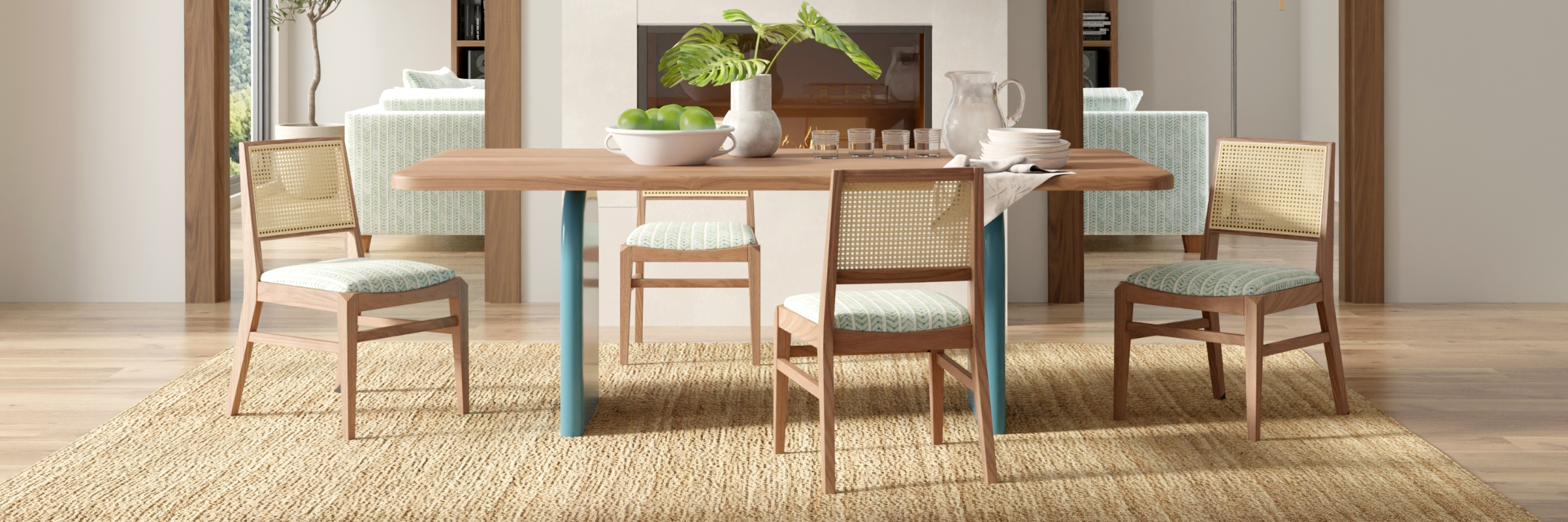 wood dining table with teal painted curved base and cane-backed wood chaits with a green geometric pattern on the upholstered seat
